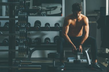 Güçlü ve yakışıklı bir genç adam dumbbells ile egzersiz yaparak portresi
