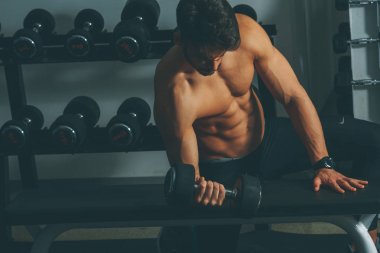 Güçlü ve yakışıklı bir genç adam dumbbells ile egzersiz yaparak portresi