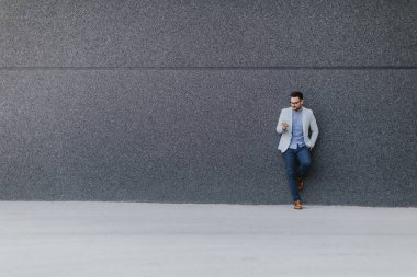 Genç adam cep telefonu el ile duvar tarafından açık duran