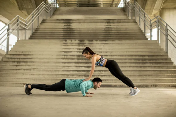 Athletic young couple doing stretching  exercises together outdoor