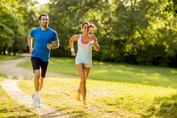 Young couple running outdoors in the park on a sunny day