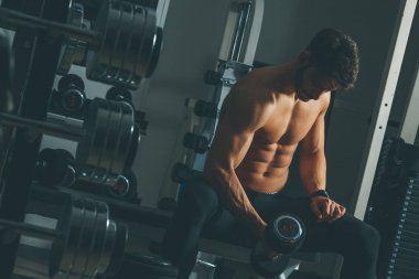 Güçlü ve yakışıklı bir genç adam dumbbells ile egzersiz yaparak portresi