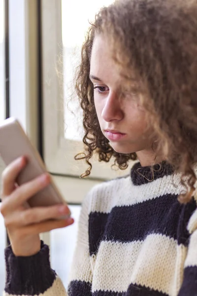 Pelo Rizado Adolescente Chica Usando Teléfono Móvil Por Ventana Casa — Foto de Stock