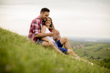 Dağda çimenlerin üzerinde çevrilmemiş seven oturan çift