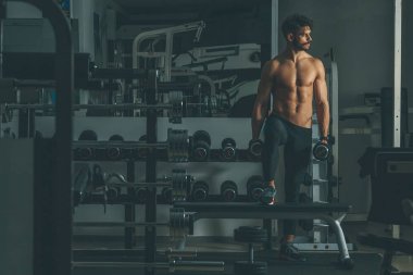 Güçlü ve yakışıklı bir genç adam dumbbells ile egzersiz yaparak portresi