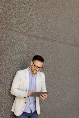 Dijital tablet kentsel ortamda açık tutan bir genç işadamı portresi