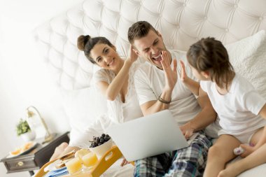 Yatağın içinde laptop ile genç aile