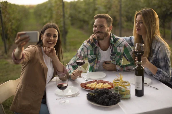 Grupo Jóvenes Sentados Junto Mesa Bebiendo Vino Tinto Tomando Selfie —  Fotos de Stock