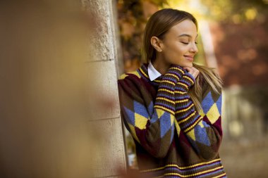 Güzel genç bayan güneşli bir sonbahar gününde dışarıda duruyor.