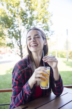 Dışarıda portakal suyu içen mutlu genç bir kadının portresi.