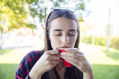 Parkta kahve içen genç bir kadının portresi