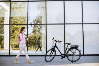 Young woman with ebicycle using on mobile phone outdoor