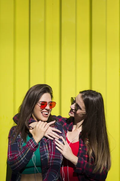 Sarı Duvarın Üzerinde Duran Iki Mutlu Kadın Arkadaş Resmi — Stok fotoğraf
