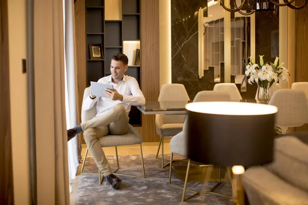 Young Man Relaxing Home Using Tablet Computer Reading Living Room — Φωτογραφία Αρχείου