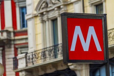 Geleneksel Milan metro tabelası İtalya 'daki eski ve güzel bir binanın arka planında.