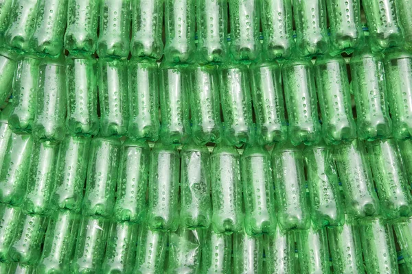 Backdrop of green plastic bottles stacked next to each other