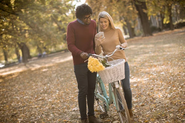 Pareja Joven Multirracial Con Bicicleta Pie Parque Otoño Uso Teléfono — Foto de Stock