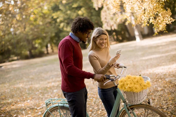 Pareja Joven Multirracial Con Bicicleta Pie Parque Otoño Uso Teléfono — Foto de Stock