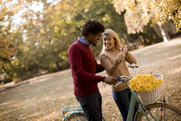 Pareja Joven Multirracial Con Bicicleta Pie Parque Otoño Uso Teléfono — Foto de Stock