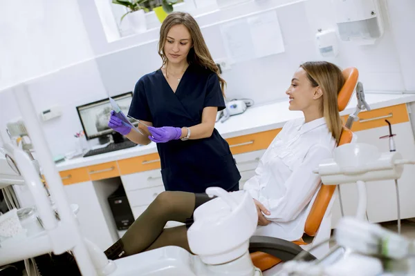 年轻漂亮的女医生 戴着防护手套 和她的病人一起在牙科诊所检查放射线 — 图库照片