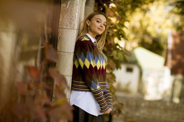 Güzel genç bayan güneşli bir sonbahar gününde dışarıda duruyor.