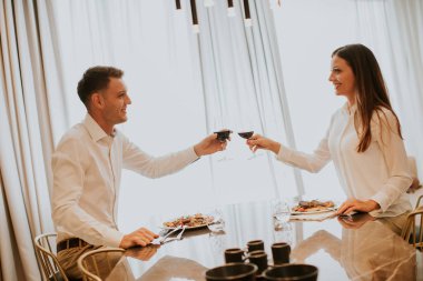 Genç ve tatlı bir çift romantik bir akşam yemeği yiyor ve lüks mutfakta kırmızı şarapla kadeh kaldırıyor.