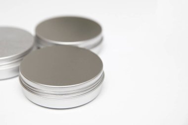 Beyaz arka planda izole edilmiş yuvarlak metal tenekelerde dudak kremi.
