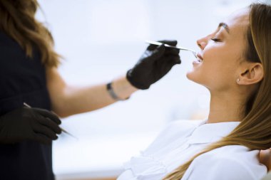 Dişçi muayenehanesinde ağız muayenesi sırasında ağzı açık bir kadının yakın çekimi.