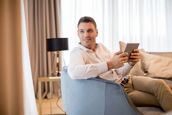 Knappe Jongeman Zitten Het Gebruik Van Digitale Tablet Luxe Appartement — Stockfoto