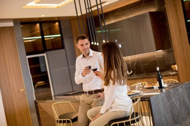 Lüks mutfakta romantik bir akşam yemeğinden sonra kırmızı şarap içen tatlı genç çift.