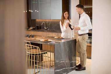 Güzel genç çift lüks mutfakta romantik bir akşam yemeği yiyor.