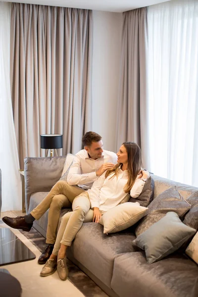 在豪华的客厅里的沙发上放松对年轻夫妇 — 图库照片