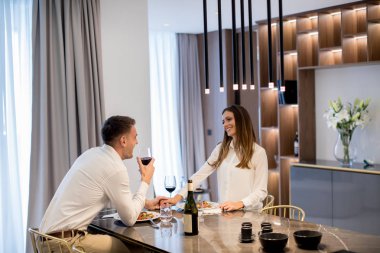 Güzel genç çift lüks mutfakta romantik bir akşam yemeği yiyor.