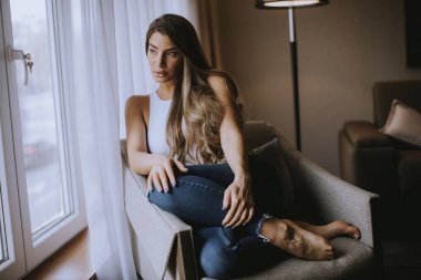 Güzel genç bir kadın, pencerenin kenarında oturuyor.