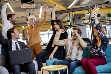 Genç iş adamlarından oluşan bir grup modern ofiste dizüstü bilgisayarla birlikte çalışıyor.