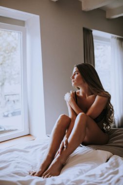 Yatakta oturan seksi genç kadın.