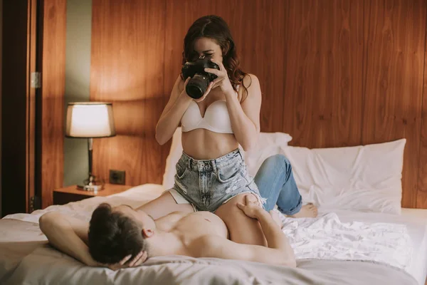 年轻女人在床上给一个有爱心的男人拍照 — 图库照片