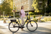 hübsche junge Frau mit modernem Elektro-E-Bike in der Stadt