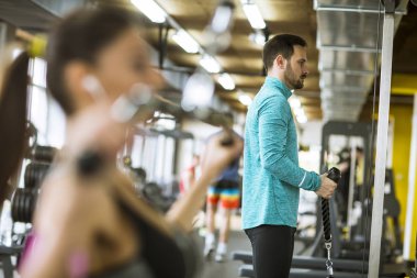 Yakışıklı genç çift modern spor salonunda vücut geliştirme egzersizleri yapıyor.