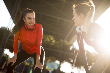 Two pretty young women doing gymnastic exercises outdoor in urban enviroment
