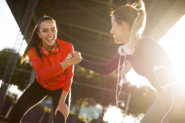 Two pretty young women doing gymnastic exercises outdoor in urban enviroment