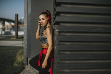 Pretty young woman takes a break after running in the urban area