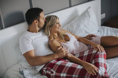 Affectionate young lovers embracing on bed at home