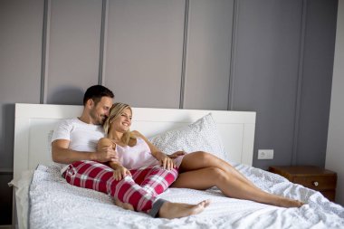 Affectionate young lovers embracing on bed at home