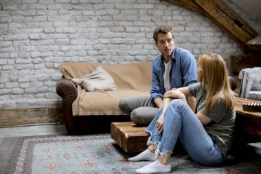 Smiling lovely young couple relaxing and watching TV at rustic home