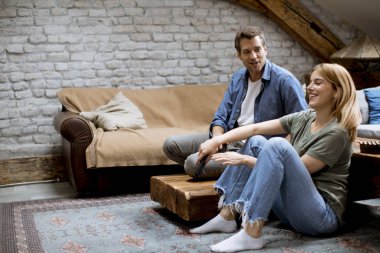 Smiling lovely young couple relaxing and watching TV at rustic home