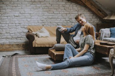 Smiling lovely young couple relaxing and watching TV at rustic home