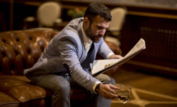 Bonito Jovem Empresário Bebendo Vinho Lendo Jornal Escritório — Fotografia de Stock