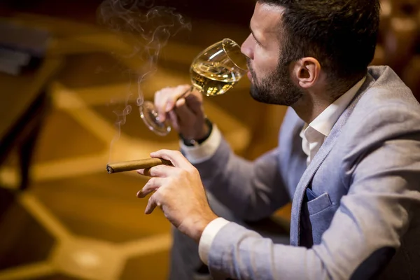 Όμορφος Νεαρός Που Δοκιμάζει Λευκό Κρασί Και Καπνίζει Πούρο — Φωτογραφία Αρχείου