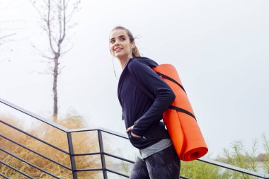 Spor salonunun arka tarafında paspasla yürüyen genç bir kadın.